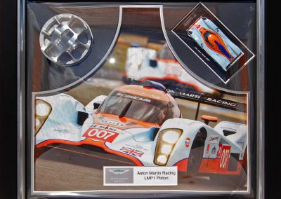 Framed Aston Martin Racing memorabilia in dome